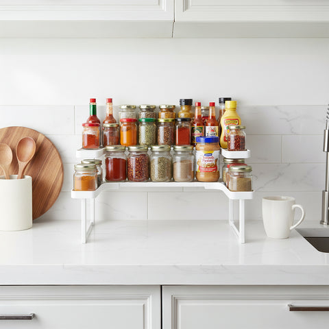 Kitchen spice rack with various jars on a white countertop